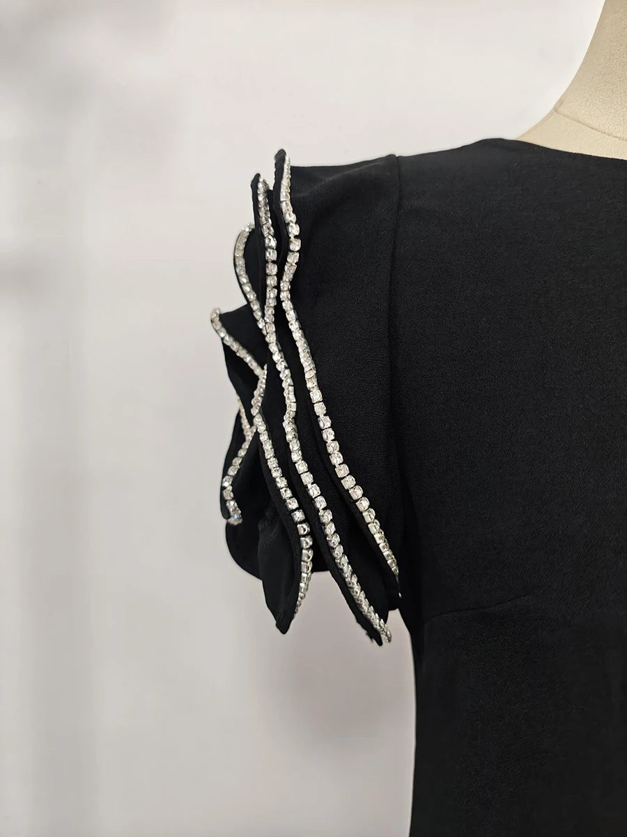 Black dress with decorative sleeves on a mannequin against a light background