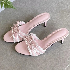 Close-up of a foot wearing a pink ruffle bow stiletto heel.