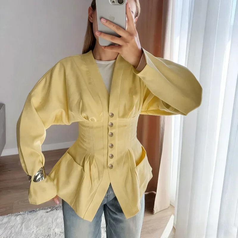 Person wearing a yellow jacket taking a mirror selfie indoors.