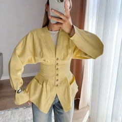 Person wearing a yellow jacket taking a mirror selfie indoors.