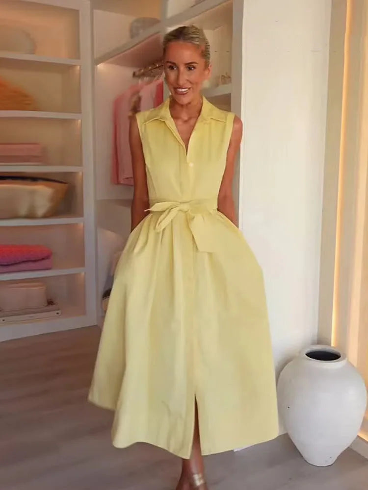 Woman wearing a yellow dress in a room with shelves and a vase.