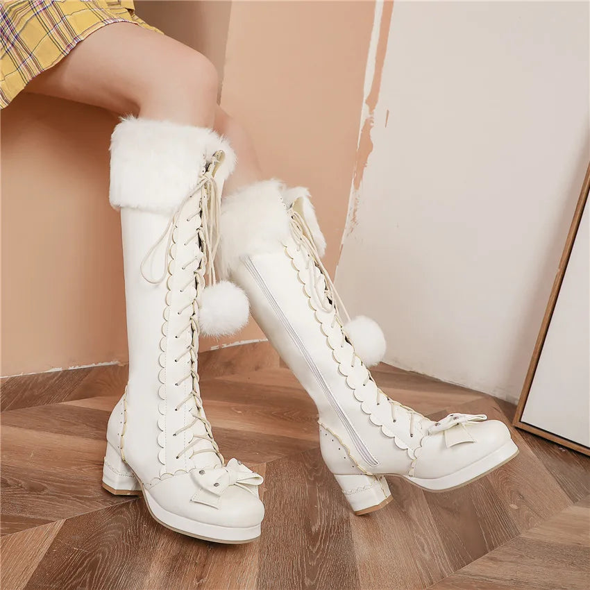 White lace-up boots with fluffy white tops worn by a person on a wooden floor.