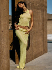 Woman in a yellow outfit standing against a textured wall.