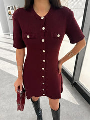 Woman wearing a burgundy knit dress with white buttons indoors.