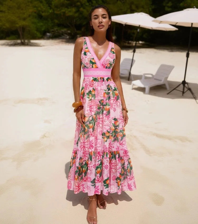 Woman wearing a pink graphic print two-piece swimwear set standing on a sandy beach.