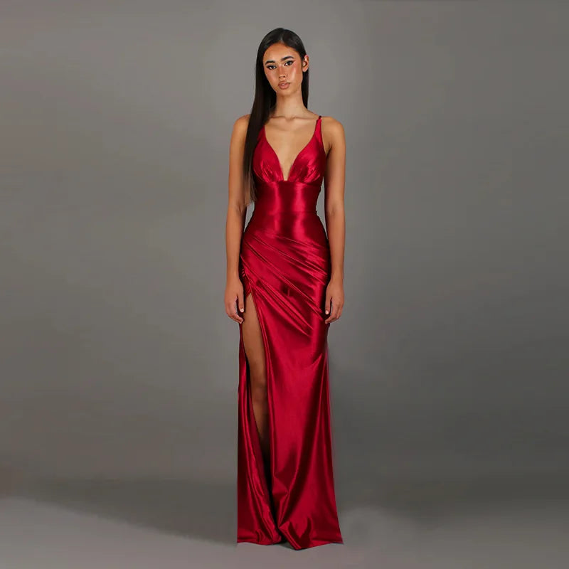 Woman wearing a red satin gown with a deep neckline and high slit on a gray background
