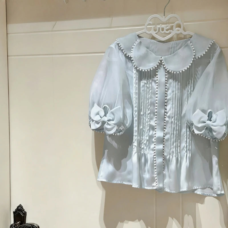 Close-up of the blue sheer puff sleeve blouse with pleated front.