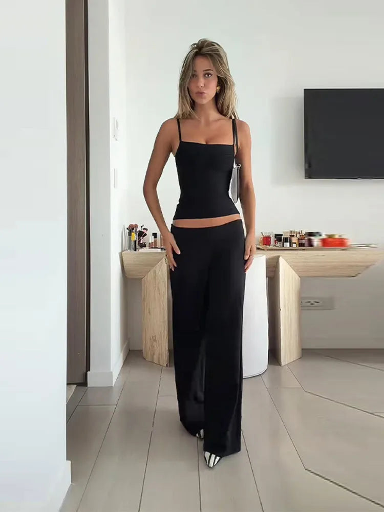 Woman in a black outfit standing in a modern room with a desk and TV.