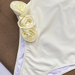 Close-up detail of rosette embellishments on a cream one piece swimsuit.