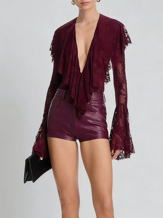 Person wearing a burgundy outfit with a deep neckline and high-waisted shorts on a light gray background