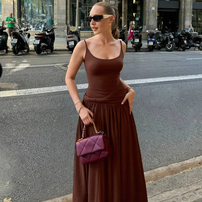 Woman in a brown dress holding a purple handbag on a city street.