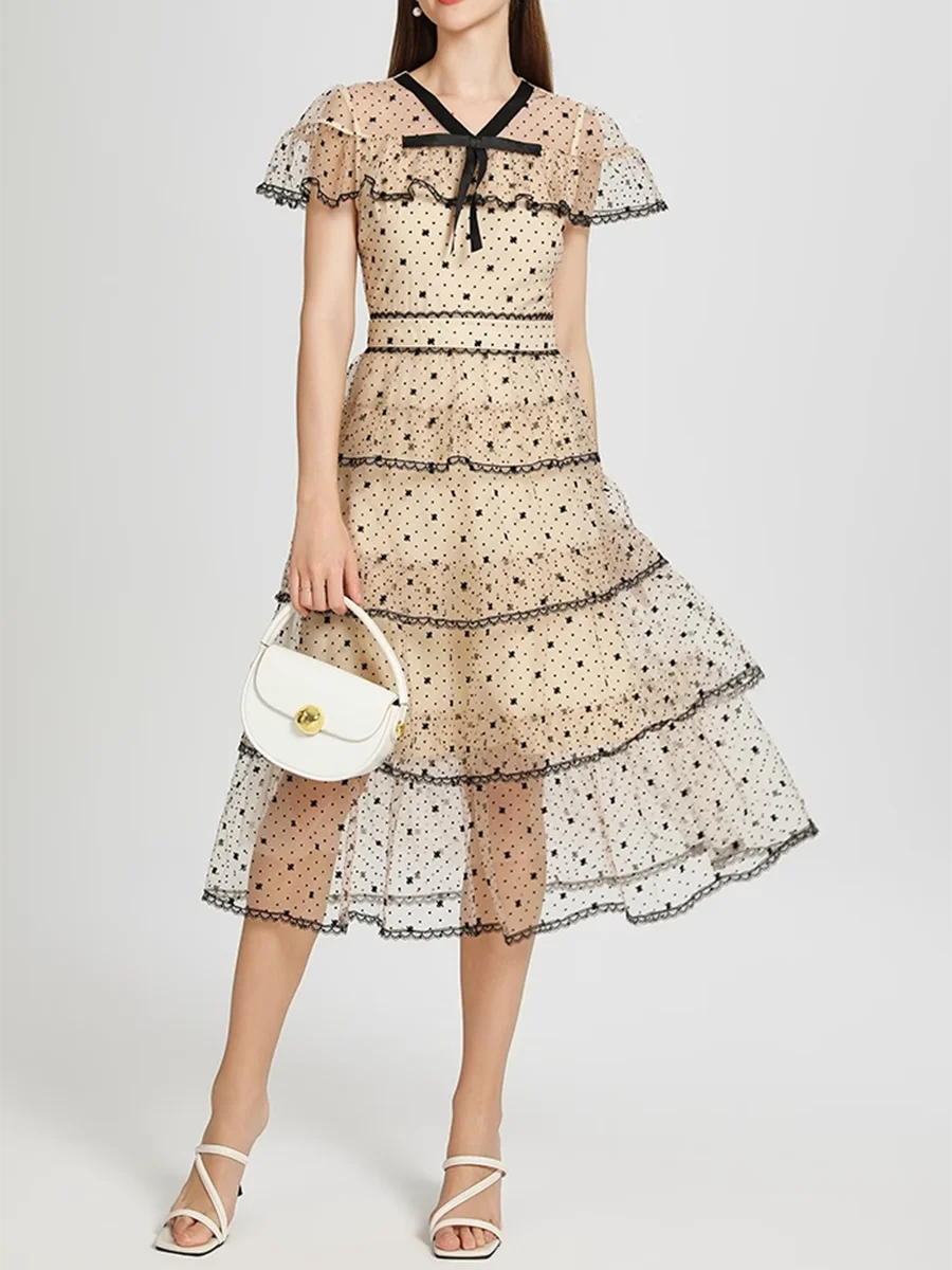 Woman wearing a layered dress with a white handbag on a light gray background