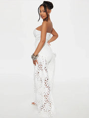 Woman wearing a white strapless dress with lace detailing on a plain background