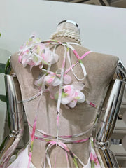 Back view of a floral print halter neck mini dress showing tie closures and blossom details.
