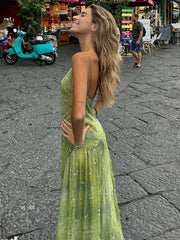 Woman in a green dress standing on a street with a scooter and people in the background