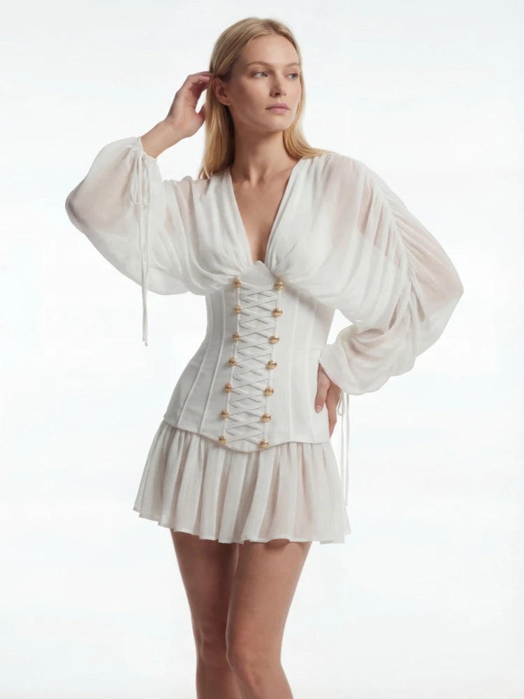Woman wearing a white outfit with long sleeves and a corset-style top on a white background
