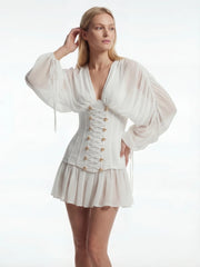 Woman wearing a white outfit with long sleeves and a corset-style top on a white background