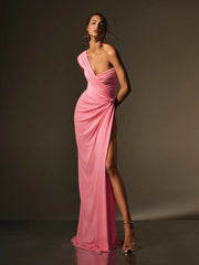 Woman wearing a pink evening gown with a high slit on a dark background
