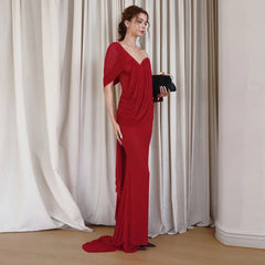 Model wearing a red draped one-shoulder dress with a clutch