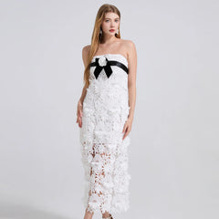 White strapless lace dress with a black bow on a white background
