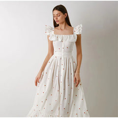 Woman wearing a white dress with ruffled sleeves against a plain background