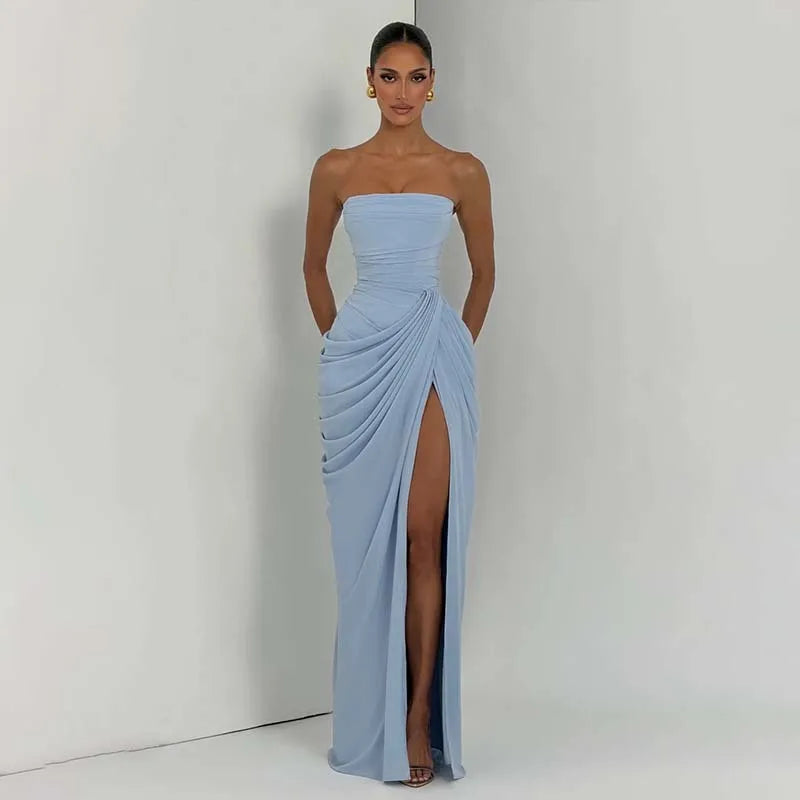 Woman wearing a strapless light blue gown with a high slit on a plain background