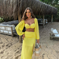 Model posing in yellow puff sleeve crop top and high slit maxi skirt set on sand