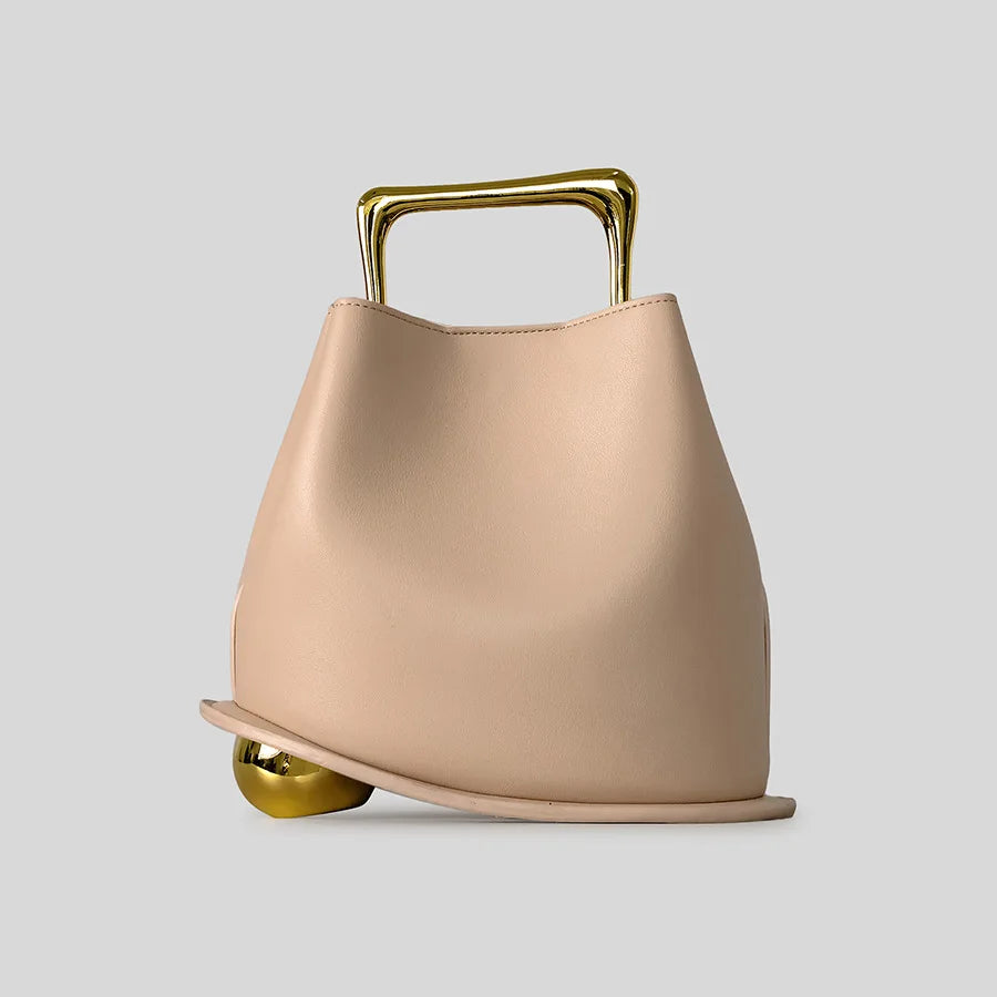 Beige handbag with gold handle and base on a light gray background