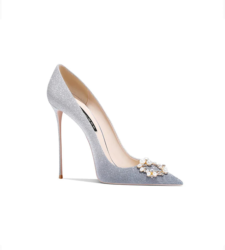 Silver glitter high heel shoe with a decorative brooch on a white background