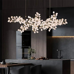 Modern chandelier hanging in a kitchen with dark walls and a dining table.