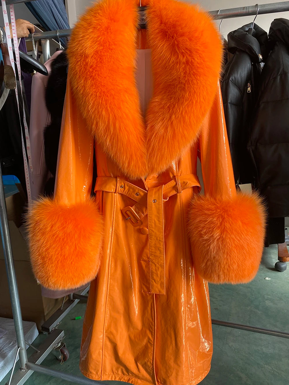 Orange fur coat with matching cuffs and collar on a rack.