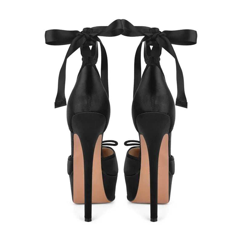 Black high-heeled shoes with ribbon ties on a white background