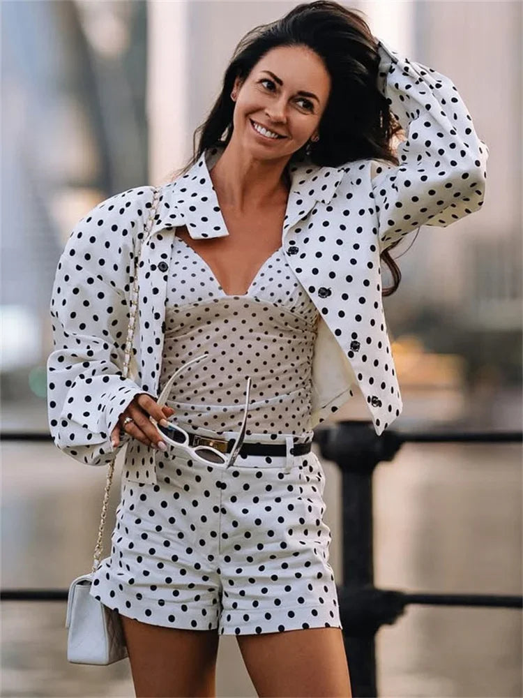 Woman wearing a polka dot outfit with sunglasses and a handbag.