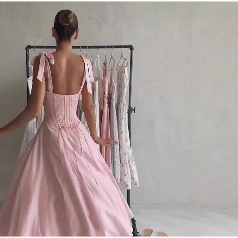 Person wearing a pink dress standing in front of a rack with other dresses.