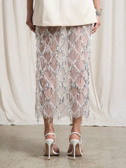 Person wearing a sheer beaded skirt with white high-heeled shoes on a neutral background