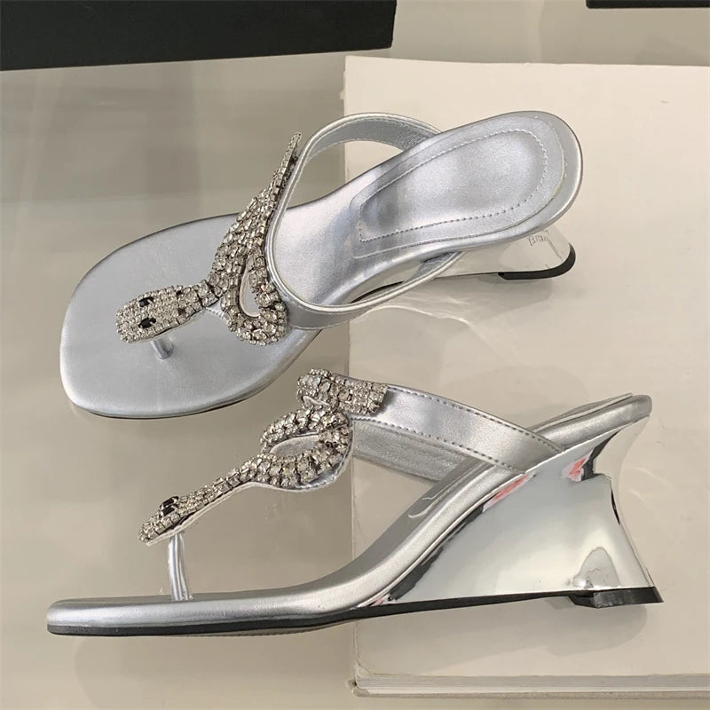 Silver high-heeled shoes with embellishments on a reflective surface
