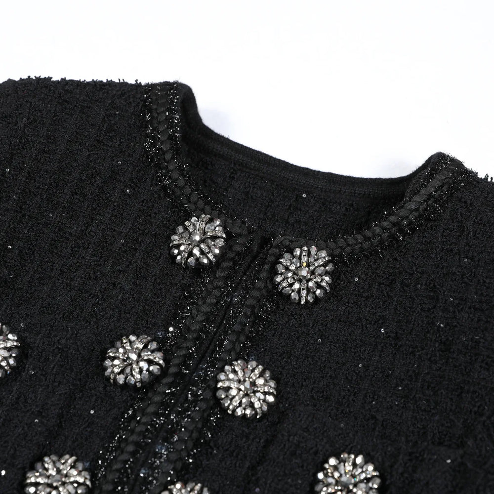 Black embroidered garment with silver embellishments on a white background