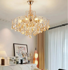 Chandelier hanging in a room with a white wall, framed picture, and lamp.