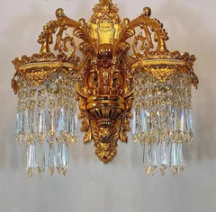 Decorative wall sconce with gold fixture and crystal accents on a plain background