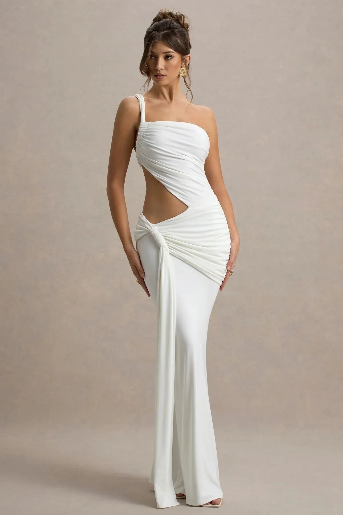 Woman wearing a white one-shoulder dress with cut-out design on a beige background