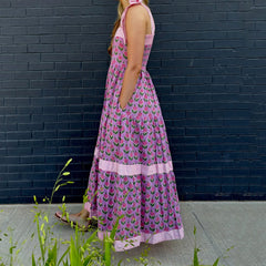 Woman wearing a pink floral dress against a dark brick wall.