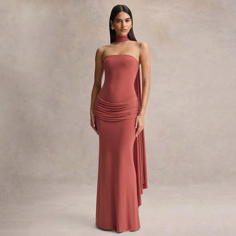 Woman wearing a strapless, long, rust-colored dress against a neutral background