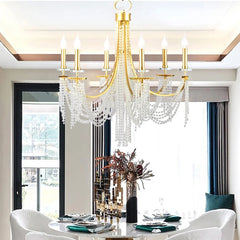 A romantic crystal chandelier with candle-style lights casting a warm glow over a dining room table. B