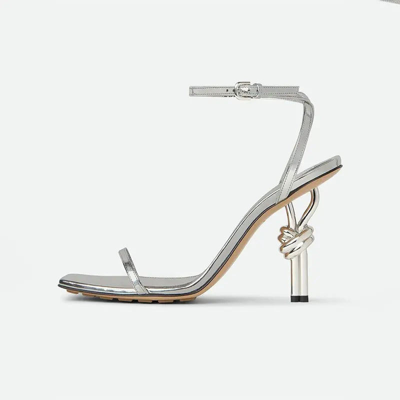 Silver high-heeled sandal with a knot detail on a white background