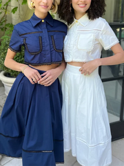Two women wearing blue and white outfits standing outdoors.