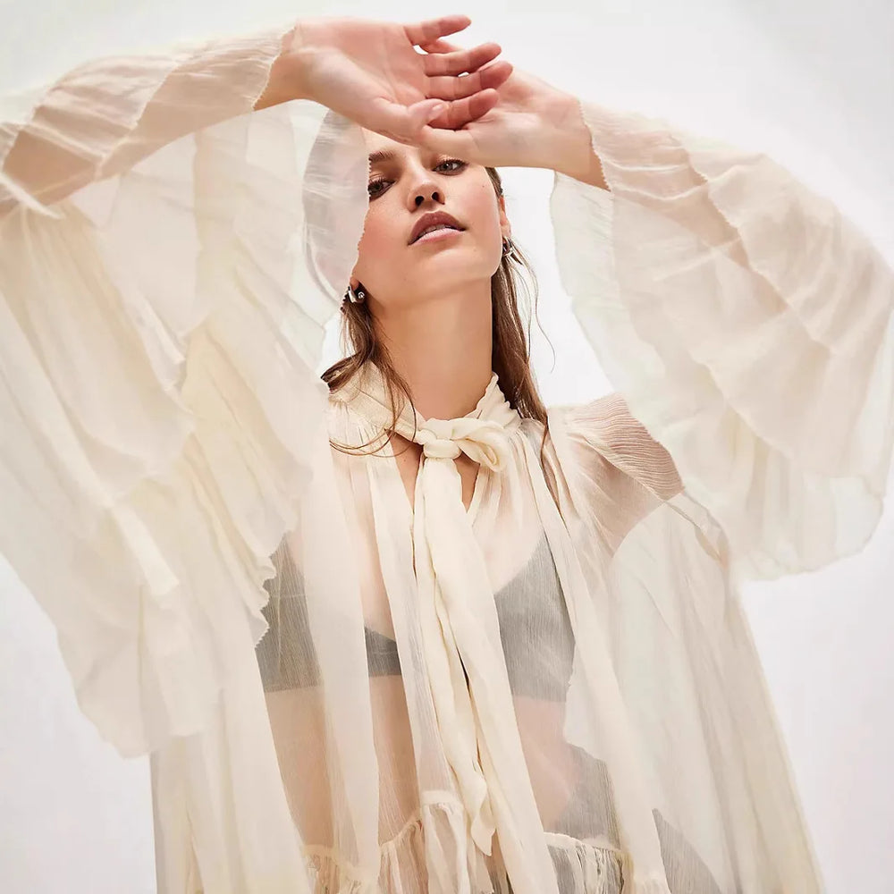 Woman wearing a sheer beige scarf with a plain background