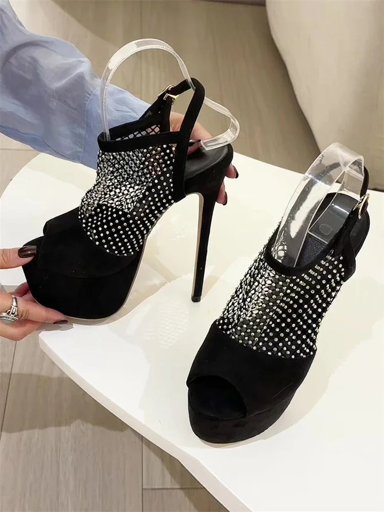 Black high-heeled shoes with crystal embellishments on a white surface.