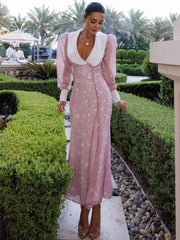 Woman in a pink dress with white collar standing in a garden setting