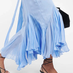 Light blue dress with ruffled skirt and black strappy sandals on a white background