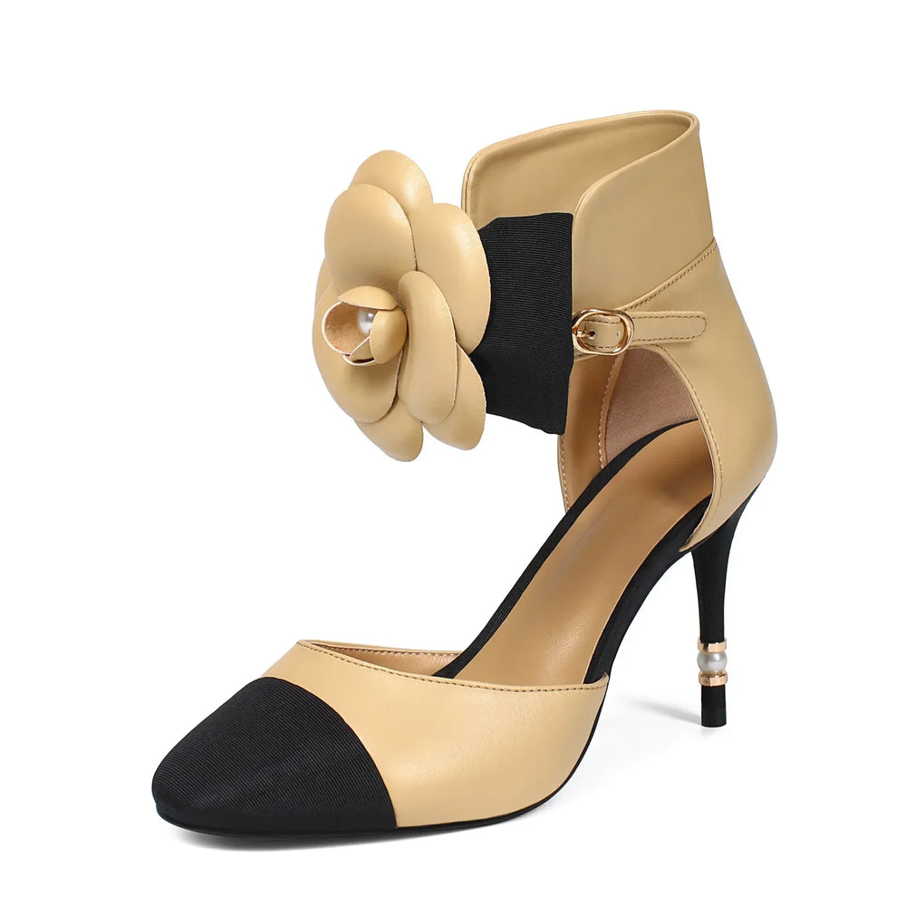 Beige and black high-heeled shoe with a decorative flower on a white background